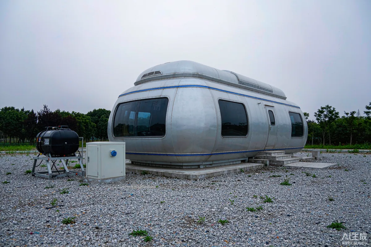 Portable generator and weatherproof inlet box beside a capsule home on a gravel pad