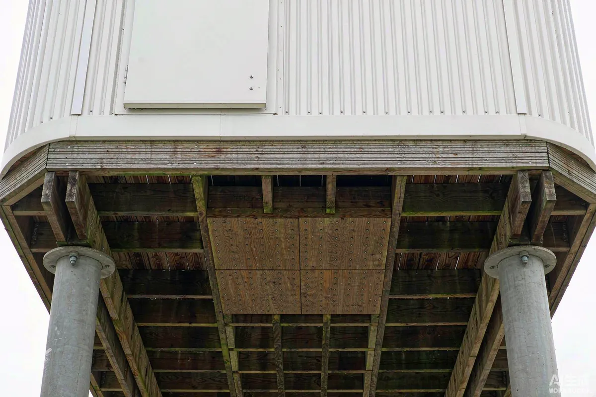 Underside of a timber deck showing reinforced joists and a service hatch beneath a prefab capsule home