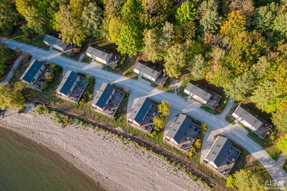 Aerial view of a small holiday park with capsule cabins on individual plots along a gravel road