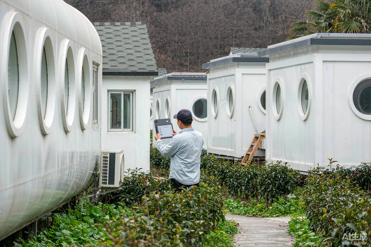 Person holding a tablet showing a wireless coverage survey outdoors between two prefab capsule homes