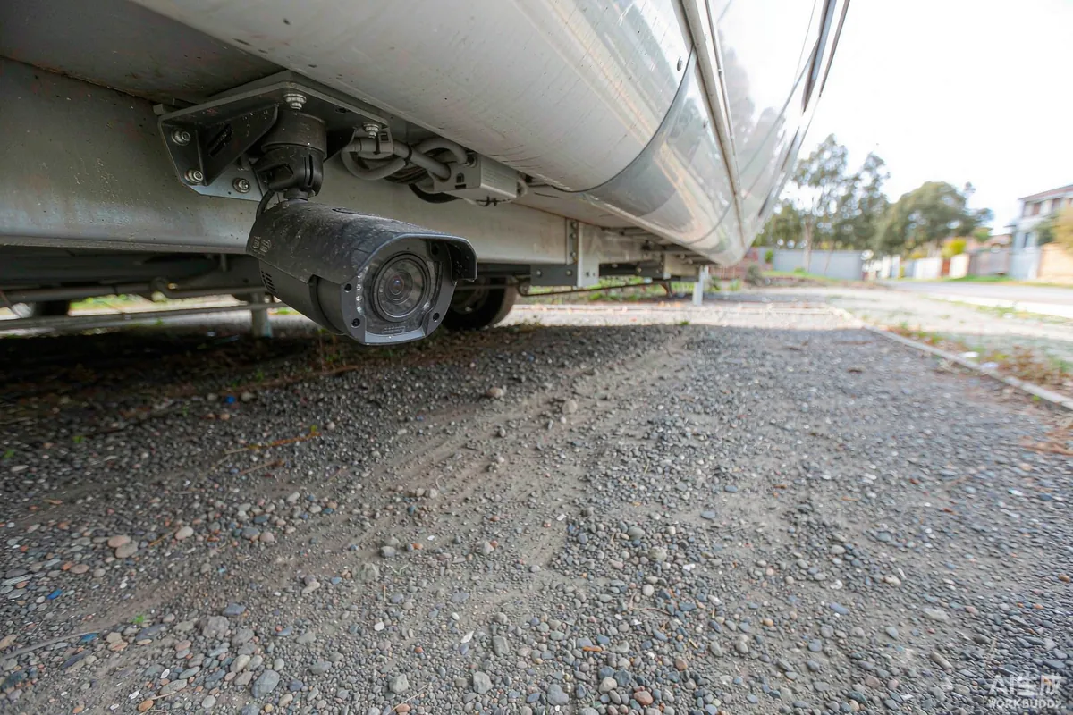Security camera mounted under the eaves of a capsule home overlooking a driveway