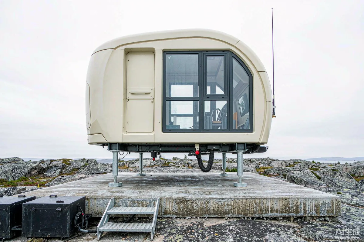 Prefab capsule home on adjustable steel support legs anchored to a concrete foundation on rocky ground