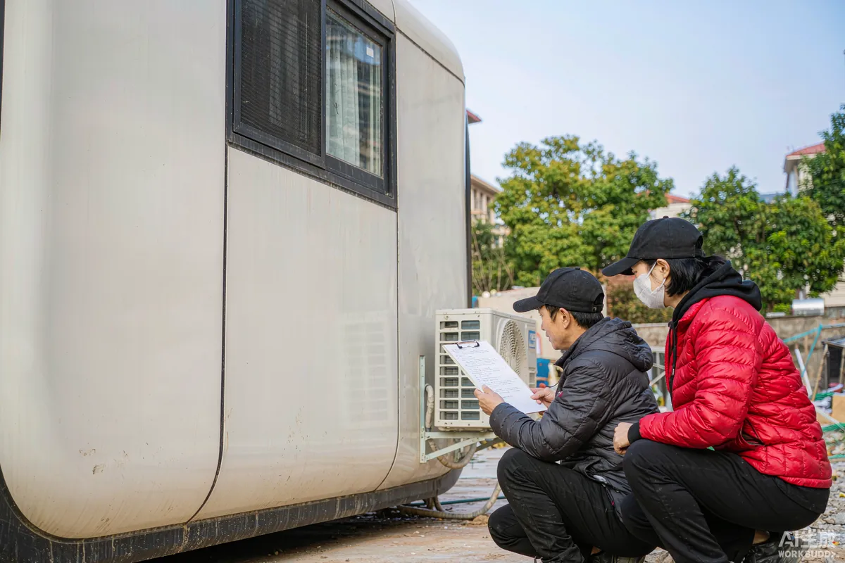 Receiving team ticking items off a printed packing list beside a delivered capsule home at a site