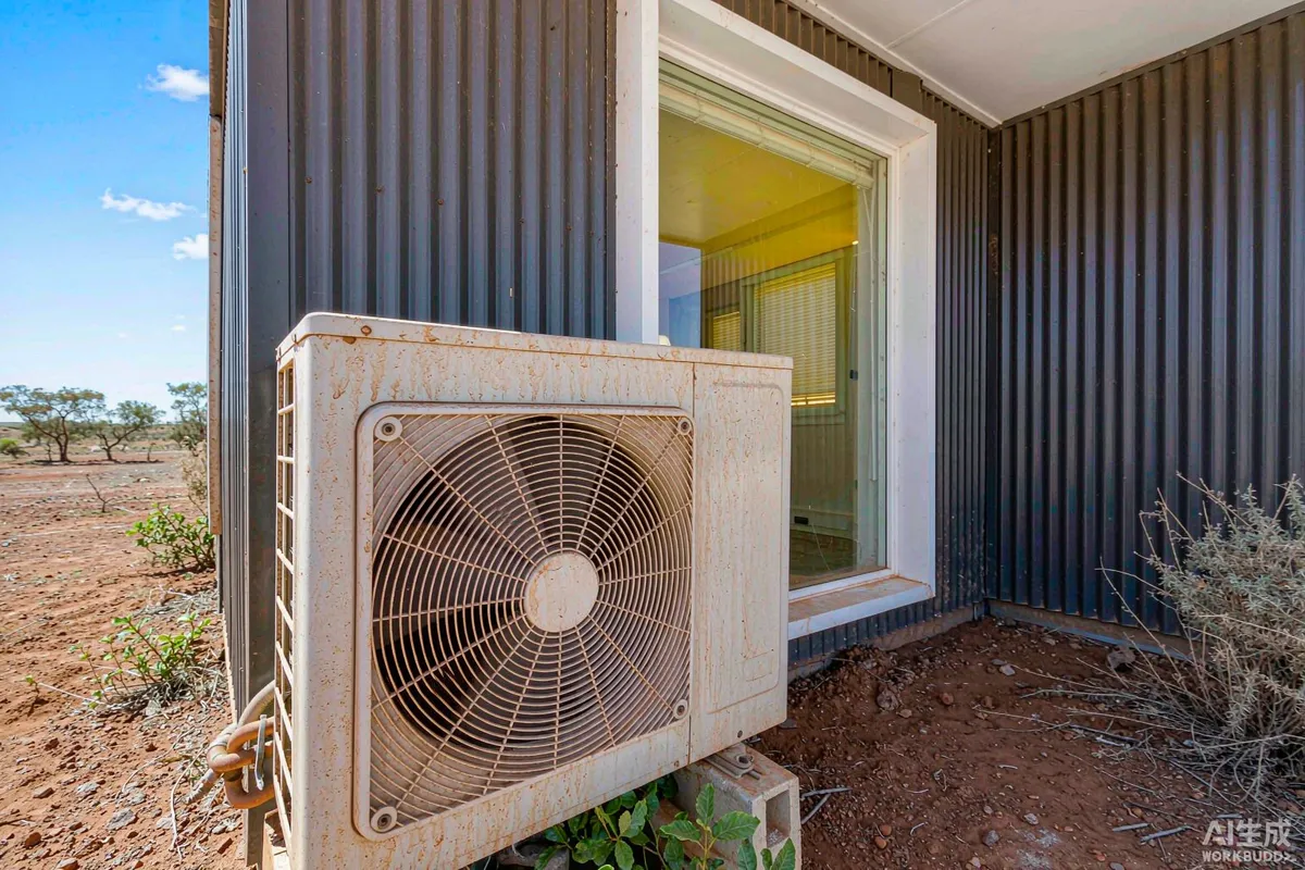 Outdoor air conditioner condenser unit mounted beside a modern pod house in a dusty yard